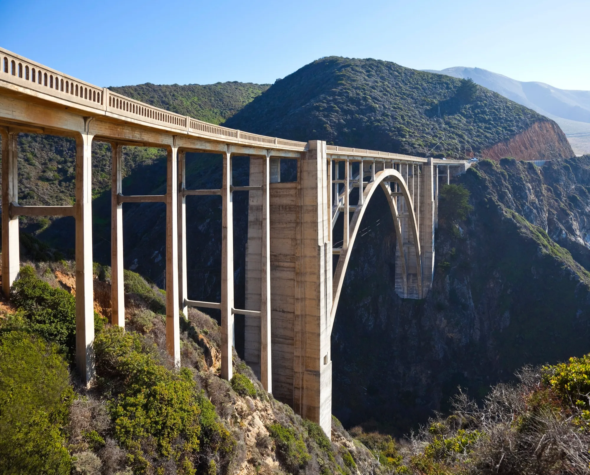 Bogenbrücke über eine Schlucht in bergiger Landschaft